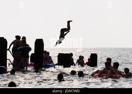 Aberystwyth Wales UK, Wednesday 21 June 2017 UK Weather: Groups of teenage boys and girls cooling off by jumping into the sea off the jetty in Aberystwyth at the end Solstice Day, and what is expected to be the last day of the current period of hot and sultry weather as the mini heat-wave continues today over the British Isles. The Met Office has warned of heavy rain and thunderstorms with the chance of localized flooding affecting much of the UK in the next 24 hours as the weather system starts to break down after many days of record hight temperatures Credit: keith morris/Alamy Live News Stock Photo