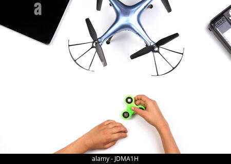 Kids hands playing with fidget spinner toy. Drone and remote controller on white background. Top view Stock Photo