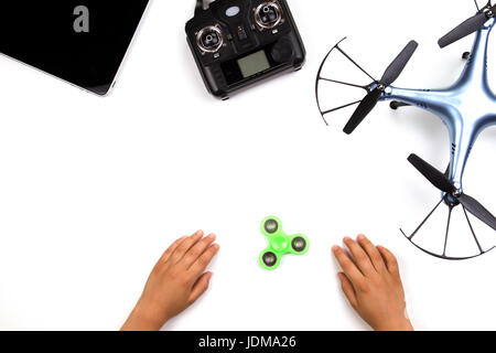 Kids hands, fidget spinner toy, drone, remote controller and tablet computer on white background. Top view Stock Photo