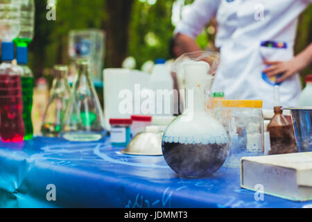 Various chemical utensils on the table. In front is a flask in which a chemical reaction Stock Photo