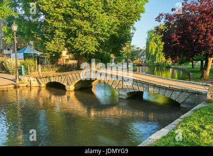 A summer morning and small stone footbridges over the River Windrush in the picturesque Cotswold village of Bourton on the Water, Gloucestershire Stock Photo