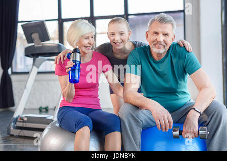 Smiling senior couple sitting on fitness balls and smiling girl in fitness class Stock Photo