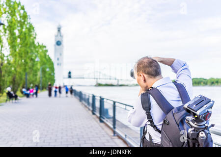 Photographer taking pictures of old port area with harbor and clock tower in old town in city in Quebec region during sunny summer day Stock Photo