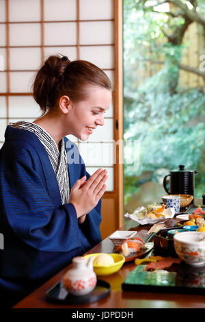 Caucasian woman wearing yukata eating at traditional ryokan, Tokyo, Japan Stock Photo