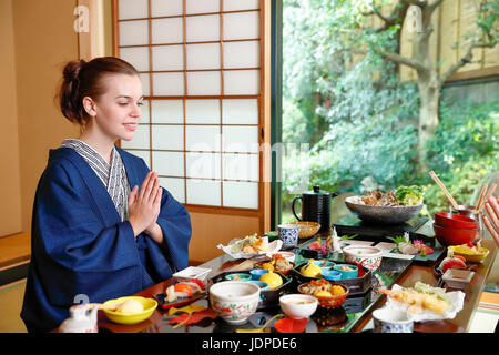 Caucasian woman wearing yukata eating at traditional ryokan, Tokyo, Japan Stock Photo