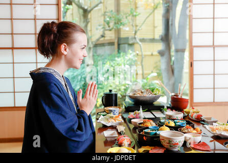 Caucasian woman wearing yukata eating at traditional ryokan, Tokyo, Japan Stock Photo