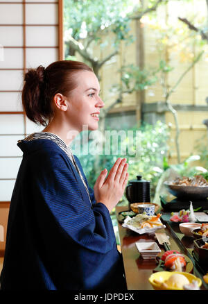 Caucasian woman wearing yukata eating at traditional ryokan, Tokyo, Japan Stock Photo