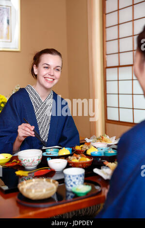 Caucasian woman wearing yukata eating at traditional ryokan, Tokyo, Japan Stock Photo