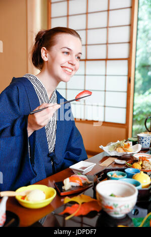 Caucasian woman wearing yukata eating at traditional ryokan, Tokyo, Japan Stock Photo