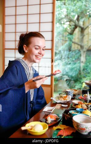 Caucasian woman wearing yukata eating at traditional ryokan, Tokyo, Japan Stock Photo