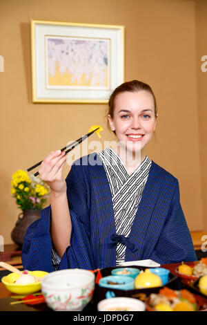 Caucasian woman wearing yukata eating at traditional ryokan, Tokyo, Japan Stock Photo