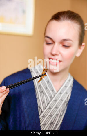 Caucasian woman wearing yukata eating at traditional ryokan, Tokyo, Japan Stock Photo