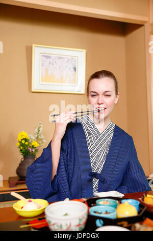 Caucasian woman wearing yukata eating at traditional ryokan, Tokyo, Japan Stock Photo