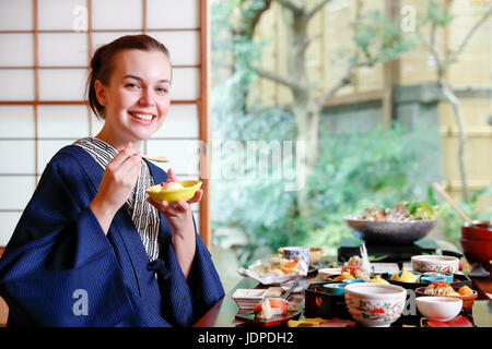 Caucasian woman wearing yukata eating at traditional ryokan, Tokyo, Japan Stock Photo