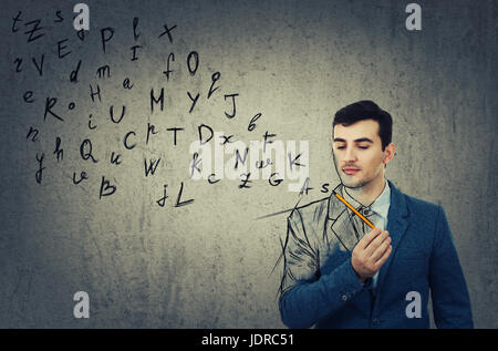 Young businessman holding a pencil in his hand  and looking at the sketched alphabet letters coming out. Education and communication concept isolated  Stock Photo