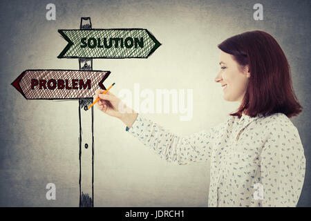 Young businesswoman holding a pencil in her hand draw an imaginative sketch of solution and problem road sign. Choice, business challenge and decision Stock Photo