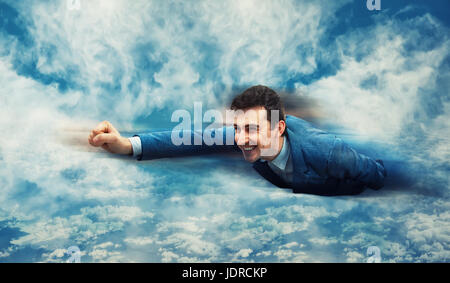 Happy, smiling businessman flying above the clouds like a superhero. Business success, opportunity and risk concept. Stock Photo