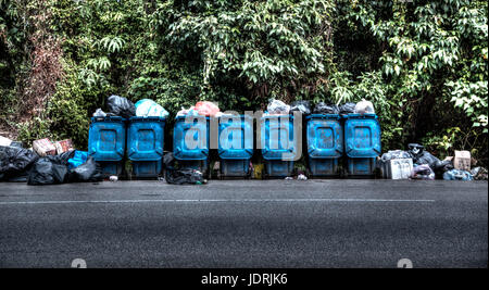 A Row of Garbage Cans Lined Overflowing at the Side of the Road Stock Photo