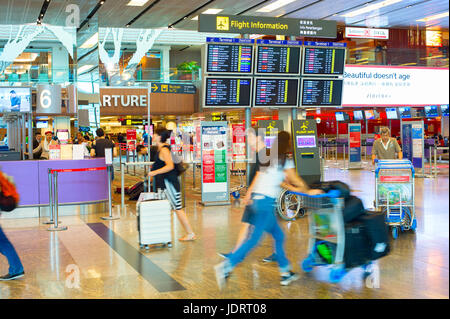 SINGAPORE - JANUARY 13, 2017: Passengers in a hurry near the ,information board in Changi Airport. Changi Airport serves more than 100 airlines operat Stock Photo