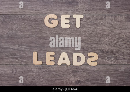 Words Get Leads made with wooden letters next to a pile of other letters over the wooden board surface composition Stock Photo