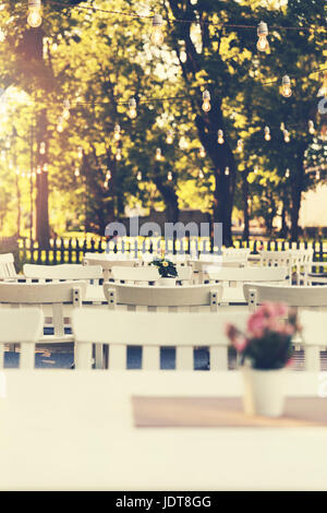 cafe outdoor garden terrace with string lights on summer evening Stock Photo