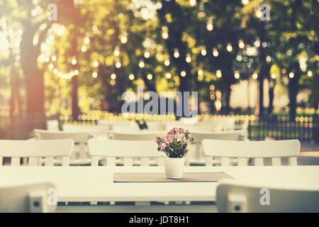 romantic outdoor restaurant in park with string lights at sunset Stock Photo