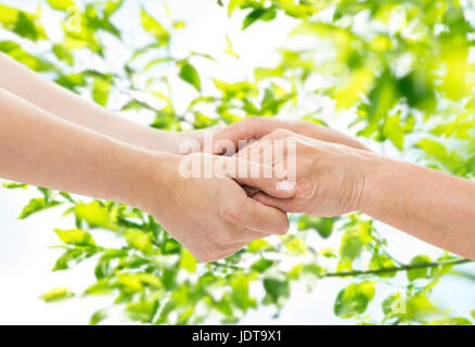 close up of senior and young woman holding hands Stock Photo