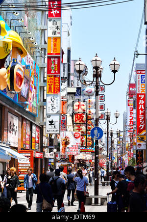 Shoppers stroll down an alleyway of signs and neon lights in Namba, Osaka, Japan Stock Photo