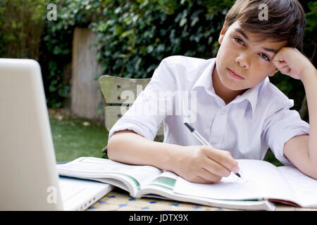 Boy doing homework in garden Stock Photo