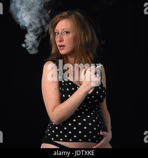 Pregnant woman smoking a cigarette Stock Photo