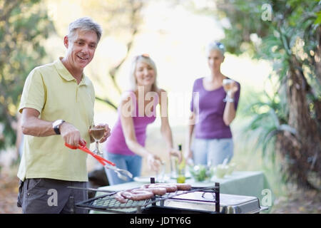 Man barbecuing sausages outdoors Stock Photo