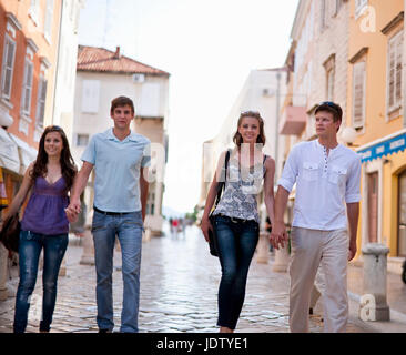 Couples walking on cobbled street Stock Photo