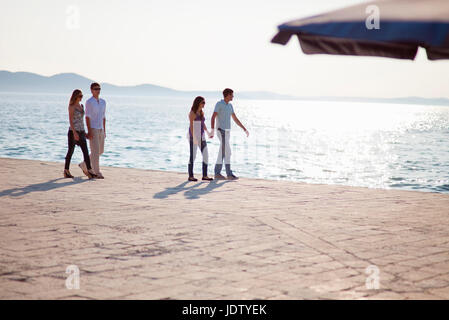 Couples walking hand-in-hand on pier Stock Photo