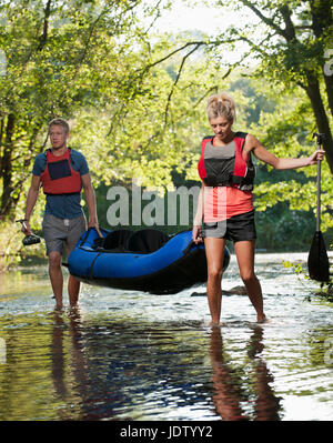 Couple carrying kayak in creek Stock Photo