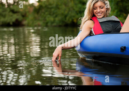 Woman dangling hand in still creek Stock Photo