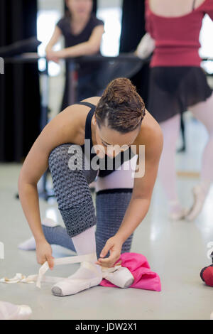 Ballet dancer tying on pointe shoes Stock Photo