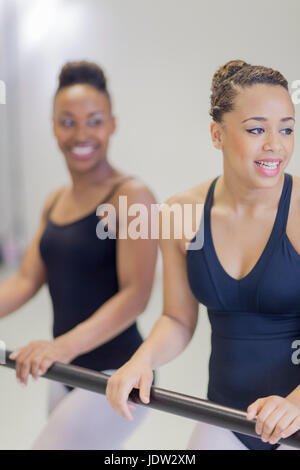 Ballet dancers standing at barre Stock Photo