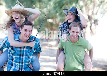 Two young men giving young women piggy backs Stock Photo