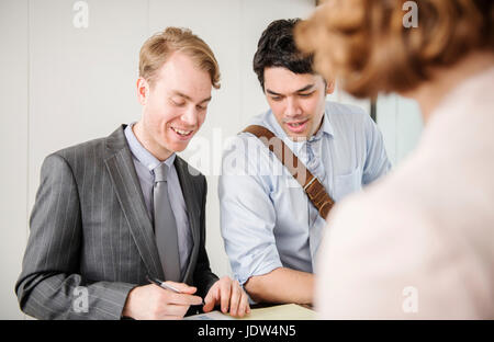 Two men signing form at reception Stock Photo
