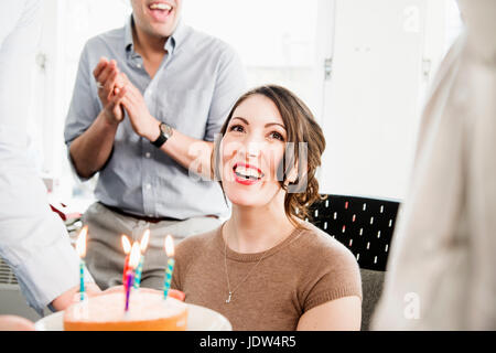 Female office worker receiving birthday cake Stock Photo