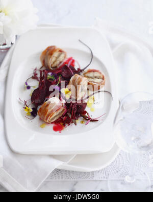 Plate of smoked eel wrapped in bacon with beetroot salad Stock Photo