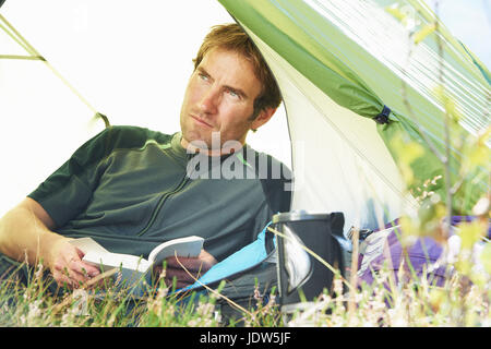 Man reading book in tent Stock Photo