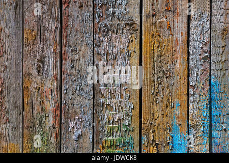 A wooden background with boards standing vertically painted with bright colors of different colors paint. Paint eventually peeled off Stock Photo