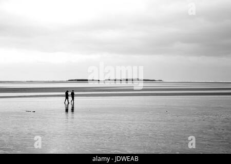 Couple walking out to Hilbre Island Stock Photo