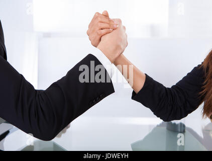 Close-up view of business colleagues arm wrestling at desk in office Stock Photo