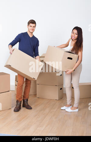 Full length portrait of young couple carrying cardboard boxes at new home Stock Photo