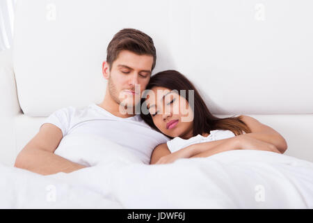 Loving young couple sleeping on mattress at home Stock Photo