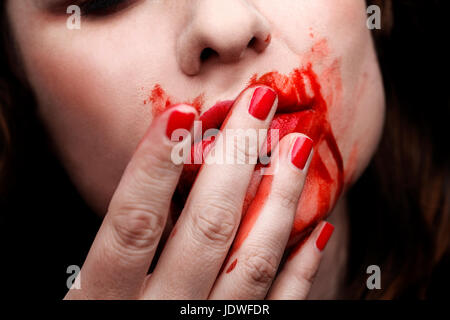 Female vampire licking blood off of her fingers Stock Photo
