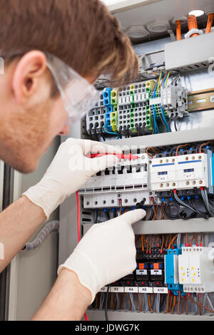 Cropped image of male electrical engineer examining fusebox with multimeter probe Stock Photo