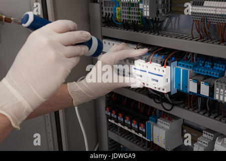 Cropped image of male technician analyzing fusebox with flashlight Stock Photo